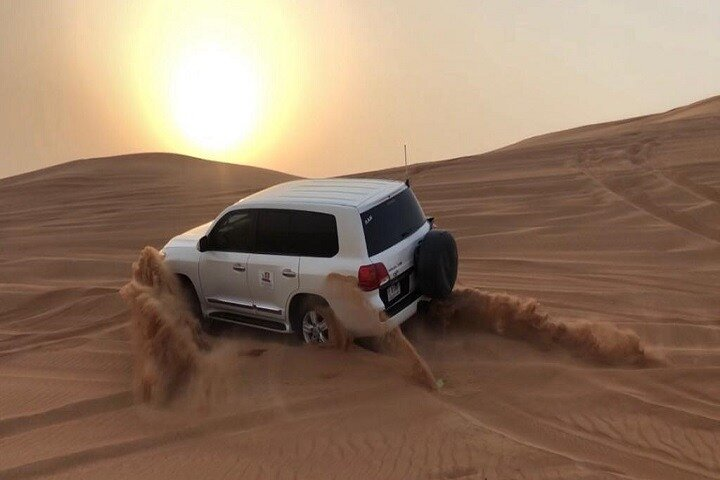 Experience the magic of the desert as you traverse stunning red dunes in a 4x4 with the sun setting behind you creating unforgettable memories in the heart of Abu Dhabi.